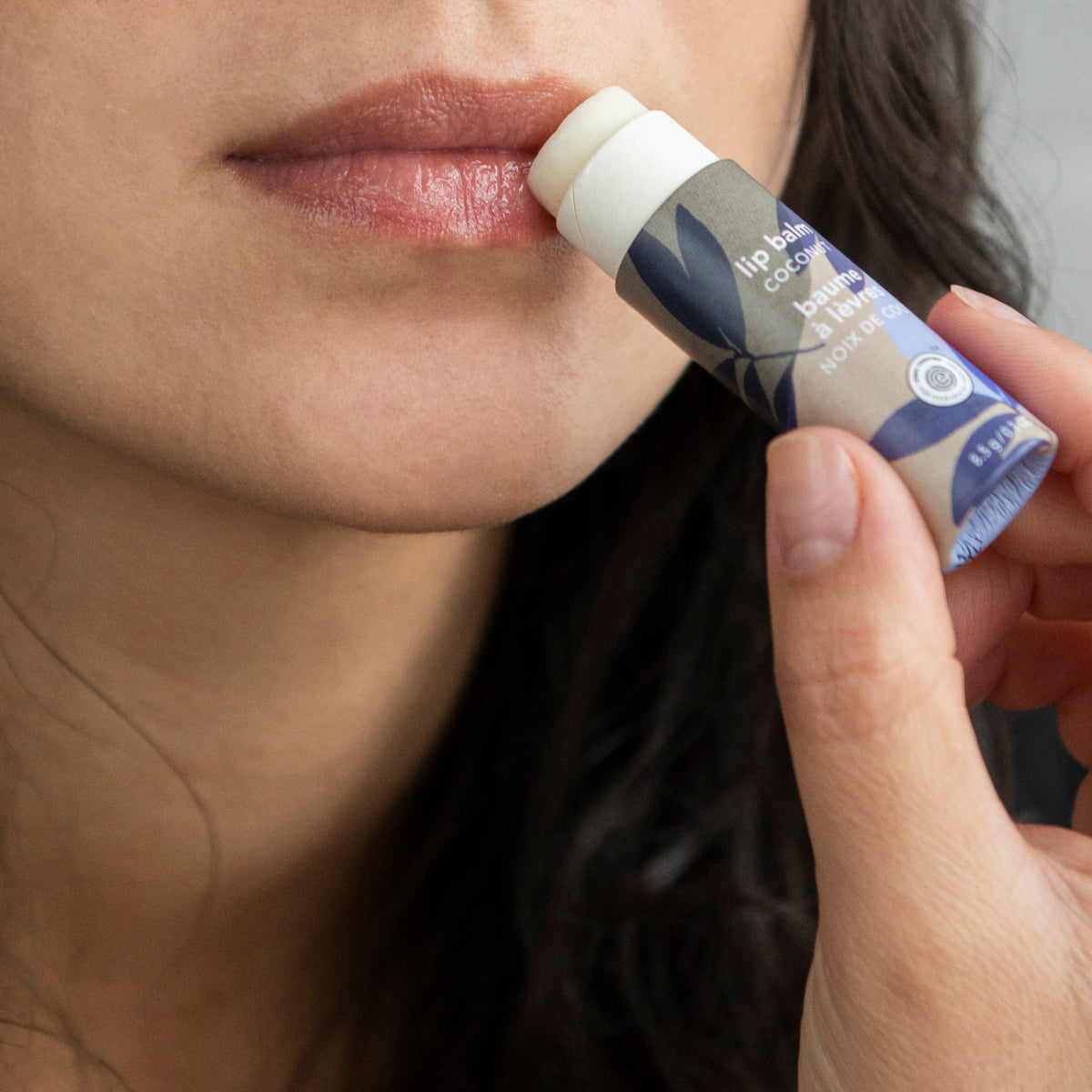 Woman applying plastic free leaves bar lip balm ATTITUDE made from natural ingredient