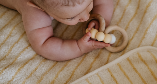 baby playing with a toy after body care with Baby Leaves products from ATTITUDE